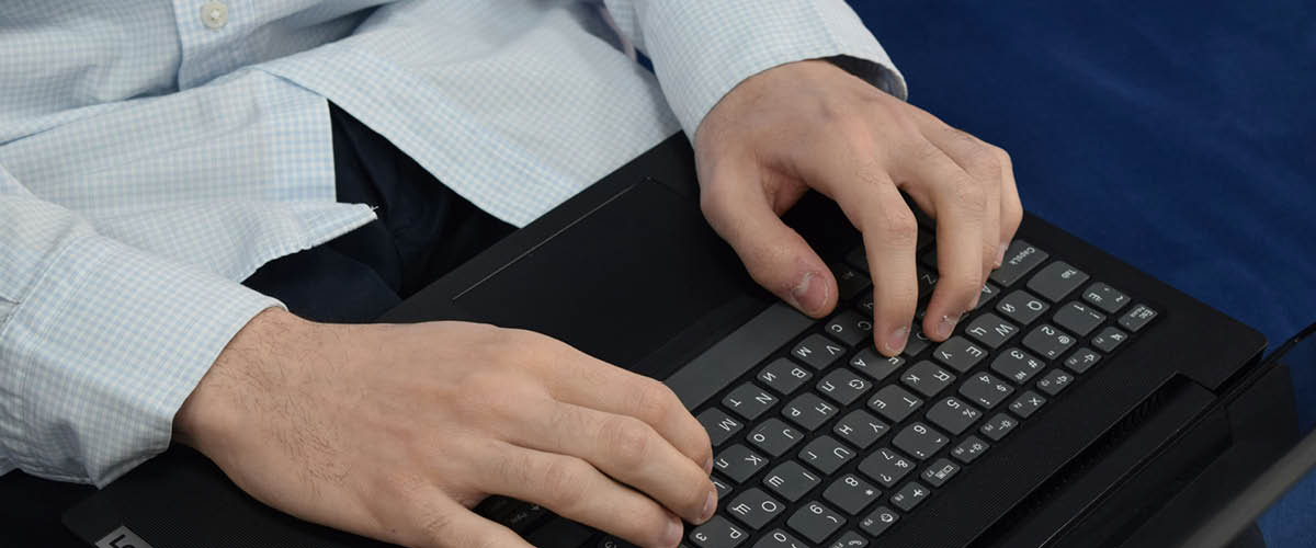 Lähikuva kannettavasta tietokoneesta, jota mies pitä sylissä.